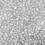 Een expert repareert een beschadigde terrazzo vloer met zorg en precisie.